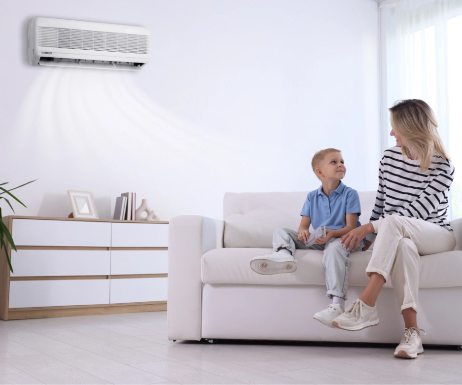Mother and child relaxing in living room with wall-mounted air conditioner providing cool air after AC service
